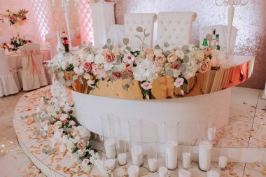 Bir restoranda tatil için romantik bir masa. Şölende yeni evliler için düğün dekoru. Çiçekler ve mumlar, boho tarzı. Gelin ve misafirler için yemek servisi..