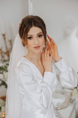 Saçında taç olan güzel bir esmer gelin güzel bir bornozla düğün için hazırlanıyor. Yakın plan düğün fotoğrafı, fotoğraf..