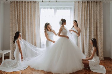 Arkadaşlar sabah gelinle sevinirler. Fotoğraf çekerler, gülümserler, gelinin elbisesini bağlamasına yardım ederler..