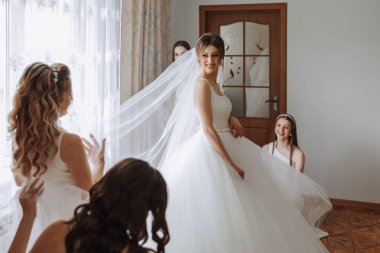 Arkadaşlar sabah gelinle sevinirler. Fotoğraf çekerler, gülümserler, gelinin elbisesini bağlamasına yardım ederler..