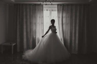 Güzel bir saç stili ve muhteşem bir elbisesi olan lüks bir gelin sabahki düğün törenine hazırlanıyor. Gelinin sabah fotoğrafı evde ya da otel odasında. Profesyonel makyaj..