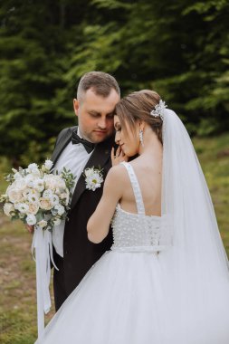 Düğün için. Aşk ve çift düğün için bahçede. Törenin ve bağlılığın kutlanması. Tarihi kaydet. Damadın, gelini ormanın arkasındaki dağlarda kucakladığına güven.