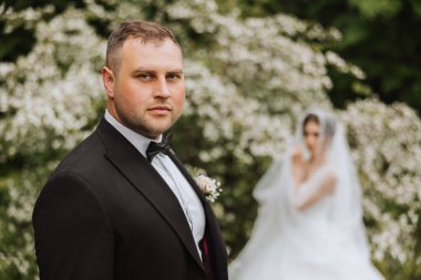 Bahar ormanında yakışıklı bir damat gelininin önünde duruyor. Güzel bir gelinlik. Parkta yürüyor. Mutlu ve sevgi dolu bir çift.