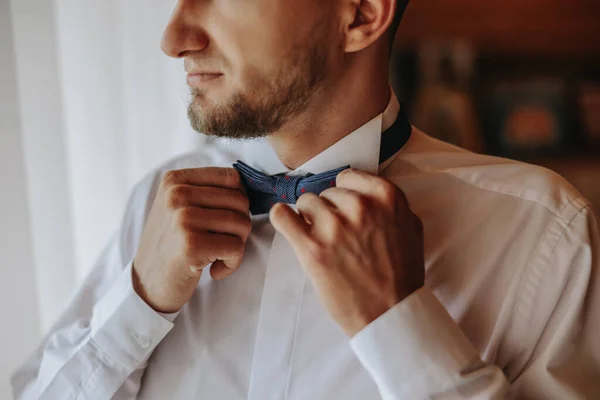 man\'s tie in hands, close-up photo of hands. The groom is preparing for the ceremony. Last preparations.