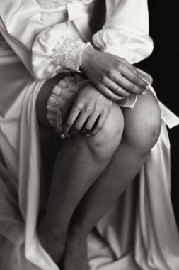 Gelinin düğünden önceki sabahı. Duvağı ve beyaz bornozlu güzel bir saç stili olan güzel bir genç kadın. Gelinliğinin yanında bir mankenin üzerinde. Profesyonel makyaj. Son hazırlıklar.