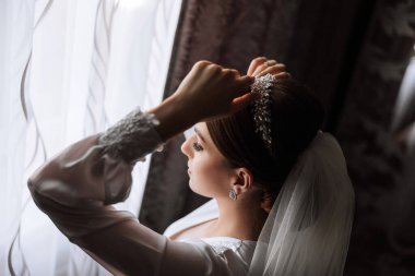 Saçında taç olan güzel bir esmer gelin güzel bir bornozla düğün için hazırlanıyor. Yakın plan düğün fotoğrafı, fotoğraf..