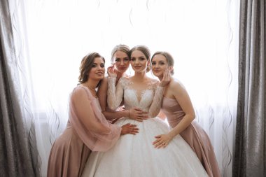 Arkadaşlar sabah gelinle sevinirler. Fotoğraf çekerler, gülümserler, gelinin elbisesini bağlamasına yardım ederler..