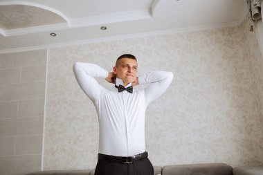 Şık bir damat düğün törenine hazırlanmak için kravatını bağlıyor. Damat sabahı. Bir iş adamı kravat takar. Damat düğün töreninden önce hazırlanıyor..