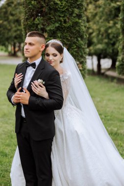 Düğün için. Aşk ve çift düğün için bahçede. Törenin ve bağlılığın kutlanması. Tarihi kaydet. Güven. Gelin ve damat kucaklaşır. Gülümse ve sev. Gelin damadı omuzlarından tutar..