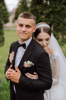 Düğün için. Aşk ve çift düğün için bahçede. Törenin ve bağlılığın kutlanması. Tarihi kaydet. Güven. Gelin ve damat kucaklaşır. Gülümse ve sev. Gelin damadı omuzlarından tutar..