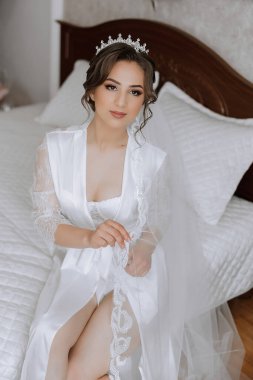 Saçında taç olan güzel bir esmer gelin güzel bir bornozla düğün için hazırlanıyor. Yakın plan düğün fotoğrafı, fotoğraf..