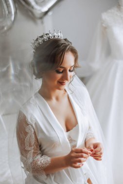 Saçında taç olan güzel bir esmer gelin güzel bir bornozla düğün için hazırlanıyor. Yakın plan düğün fotoğrafı, fotoğraf..