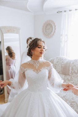 Güzel bir saç stili ve muhteşem bir elbisesi olan lüks bir gelin sabahki düğün törenine hazırlanıyor. Gelinin sabah fotoğrafı evde ya da otel odasında. Profesyonel makyaj..