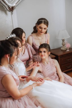 Arkadaşlar sabah gelinle sevinirler. Fotoğraf çekerler, gülümserler, gelinin elbisesini bağlamasına yardım ederler..