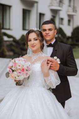 Düğün için. Aşk ve çift düğün için bahçede. Töreni ve bağlılığı kutluyoruz. Tarihi kaydet. Güven. Damat gelini nazikçe omuzlarından kucaklıyor. Birbirine aşık bir çift. Düğün portresi