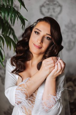 Saçında taç olan güzel bir esmer gelin güzel bir bornozla düğün için hazırlanıyor. Yakın plan düğün fotoğrafı, fotoğraf..