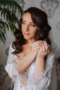 Saçında taç olan güzel bir esmer gelin güzel bir bornozla düğün için hazırlanıyor. Yakın plan düğün fotoğrafı, fotoğraf..