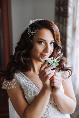 Genç bir gelinin harika bir portresi. Uzun kıvırcık saçlı, düğün makyajı ve mücevher çelengi olan güzel bir gelin. İçi güzel kahverengi gözlü bir düğün fotoğrafı modeli..