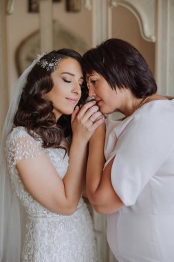 Güzel ve mutlu bir anne ve kızı, gelin, yan yana duruyorlar. Ebeveynler için en iyi gün. Düğünde hassas anlar.