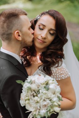 Düğün için. Aşk ve çift düğün için bahçede. Töreni ve bağlılığı kutluyoruz. Tarihi kaydet. Güven. Damat gelini kucaklıyor. Şefkatli öpücükler. Birbirine aşık bir çift. Düğün portresi