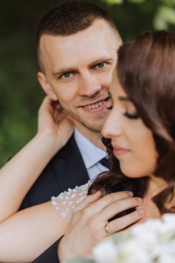 Düğün için. Aşk ve çift düğün için bahçede. Töreni ve bağlılığı kutluyoruz. Tarihi kaydet. Güven. Damat gelini kucaklıyor. Şefkatli öpücükler. Birbirine aşık bir çift. Düğün portresi