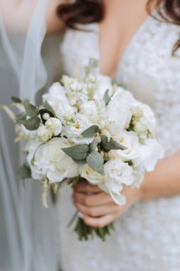 Gelin bir düğün buketi tutuyor. Kesilmiş fotoğraf. Düğündeki detaylar. Beyaz dantel elbise