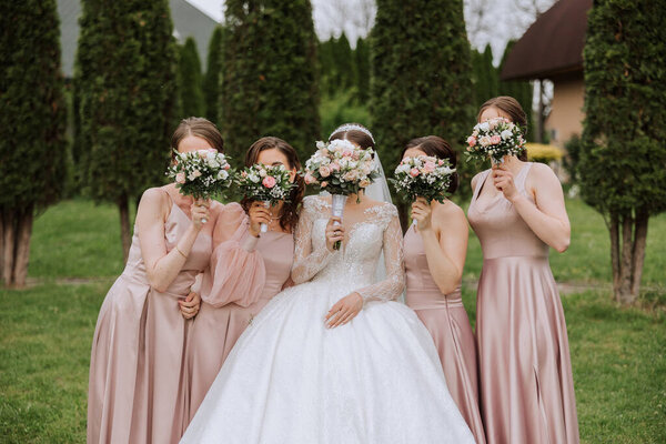 Group portrait of the bride and bridesmaids. Невеста в свадебном платье и подружки невесты в розовых или порошковых платьях и проведение стильные букеты в день свадьбы.