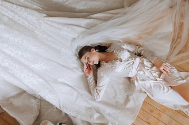 Güzel, genç bir gelin kız, güzel bir bornozla yatıyor. Düğün töreninden önce gelinin sabahı.