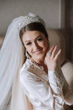 Düğün töreninden önce sabahları sabahlık giymiş güzel bir gelin. Gelinin saç stili inanılmaz. Doğal ve modern makyaj. Sabahlık giymiş genç bir gelinin portresi.