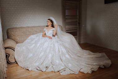 Uzun gelinlik ve duvak giymiş genç esmer otel odasında. Büyüleyici bir gelin, uzun boylu, muhteşem beyaz elbisesiyle düğünden önceki sabah.