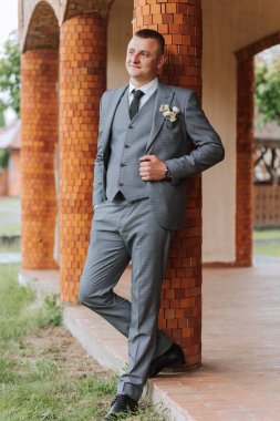 Yazın doğadaki damadın portresi. Zarif gri takım elbiseli şık, uzun boylu damat. Doğada bir iş adamı. Başarılı bir adamın portresi. Damadın düğün portresi.