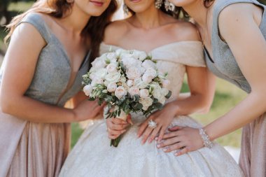 Gelinin kız arkadaşları. Gelin elinde bir buket tutuyor, yakın plan fotoğraf. Doğada düğün. Aynı elbiseli kızlar..
