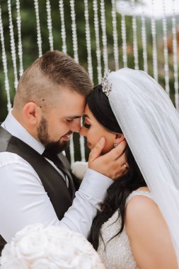 Doğada bir çiftin birbirine bakarken çekilmiş yakın plan fotoğrafı. Gelin ve damat doğanın ortasında birbirlerine bakıyorlar. Gözlerinde şefkat ve sevgi.