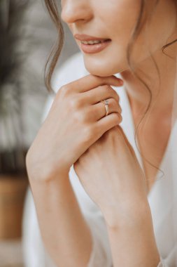 Gelinin elleri beyaz bir gelinlik içinde, altın bir alyans ve elmas bir yakın plan. Düğün fotoğrafı.