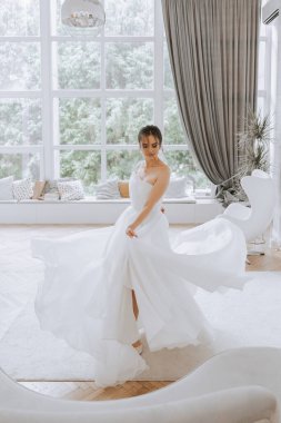 Uzun gelinlik ve duvak giymiş genç esmer otel odasında. Büyüleyici bir gelin, uzun boylu, muhteşem beyaz elbisesiyle düğünden önceki sabah.