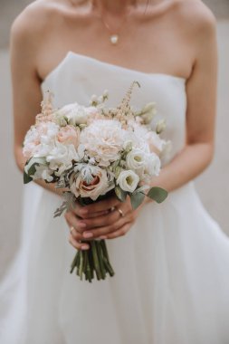Gelin elinde bir buket beyaz ve pembe çiçek tutuyor. Yakın plan fotoğraf. Düğün detayları. Yüksek kalite fotoğraf