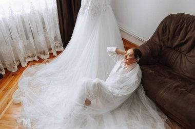 Odasında uzun peçeli, bornoz giymiş güzel bir gelin. Bir mankenin üzerinde gelinlik. Düğün töreninden önceki sabah gelin..