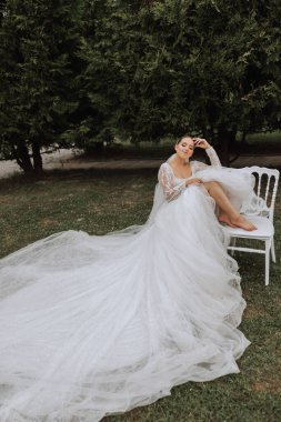 Uzun treni olan güzel bir gelin. Beyaz elbiseli gelin ve doğada uzun bir tren bir yaz günü. Yaz düğünü.