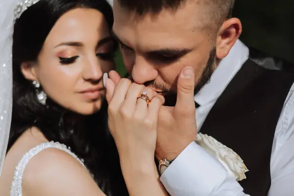 Wedding kiss. Groom kisses bride\'s hand. Weddng love. Close-up of a young man kissing his wife\'s hand with gold ring while making a marriage proposal.