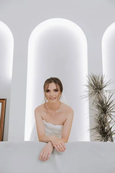 ホテルの部屋の花嫁の肖像画 美しい女の子が白いウェディングドレスを着ています 現代の結婚式のヘアスタイル ナチュラルメイク — ストック写真