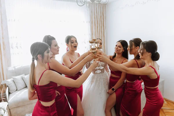 Photo bride with her friends drinking champagne from glasses. Cropped shot of a beautiful young bride and her bridesmaids having champagne before the wedding.