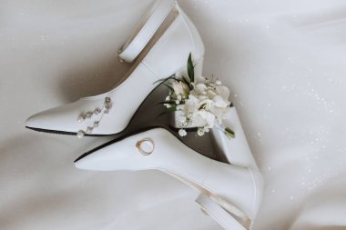 Gelinin nişan yüzüğü, topuklular, parfüm. Gelinin düğün detayları. Çiçekler. Güzel ışık. Gelinlik