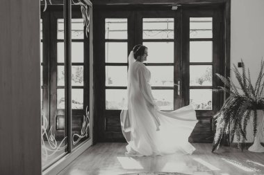 Düğün töreninden önce sabahları sabahlık giymiş güzel bir gelin. Gelinin saç stili inanılmaz. Doğal ve modern makyaj. Sabahlık giymiş genç bir gelinin portresi.