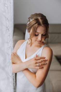 Düğün töreninden önce sabahları sabahlık giymiş güzel bir gelin. Gelinin saç stili inanılmaz. Doğal ve modern makyaj. Sabahlık giymiş genç bir gelinin portresi.