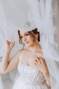 Beyaz gelinlik içinde duvak tutan genç bir gelin otel odasında esmer gelin portresi, düğünden önceki sabah..