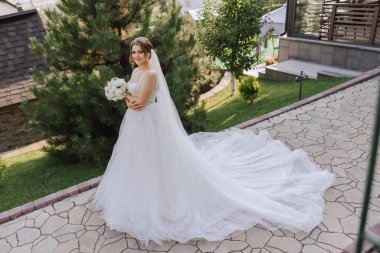 Uzun treni olan güzel bir gelin. Beyaz elbiseli gelin ve doğada uzun bir tren bir yaz günü. Yaz düğünü.