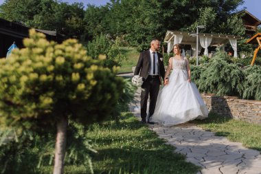 Yakışıklı bir damat ve bembeyaz elbiseli zarif bir gelin yaz parkında yürüyorlar. Mutlu gelin ve damat en güzel günlerine hazırlanıyor..
