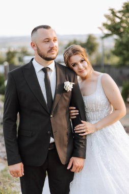 Gelin ve damat kucaklaşır. Gelin damadı nazikçe omuzlarından kucaklıyor. Güzel bir düğün çifti. Yeni evlilerin ilişkilerinde romantizm kavramı. Balayı.