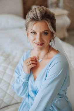 Düğün töreninden önce sabahları sabahlık giymiş güzel bir gelin. Gelinin saç stili inanılmaz. Doğal ve modern makyaj. Sabahlık giymiş genç bir gelinin portresi.