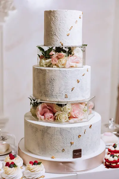 a three-tiered wedding cake decorated with flowers stands on a decorative stand. Decorative wedding cake. Beauty is in the details.